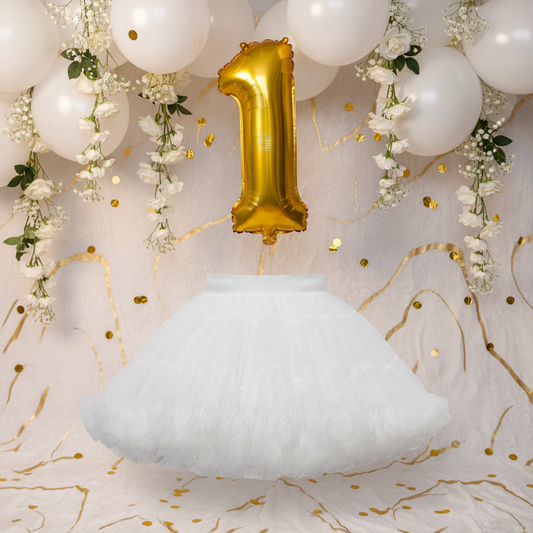 White Tutu Skirt styled with white balloons and gold confetti in an elegant 1st birthday party scene