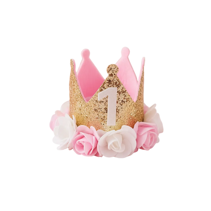 First Birthday Crown Hat styled with rose petals and gold confetti on pastel pink background